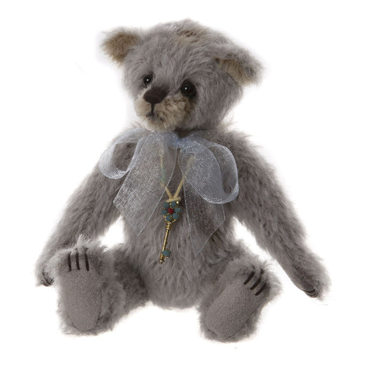This is Little Boy Blue by Charlie Bears. This bear has a shaggy, long-pile coat that appears slightly wiry with a low sheen. The coat colours are gray and beige. The muzzle and inner ears are beige while the rest of the head, body and tummy are gray; the paw soles are a darker gray felt and the paw toes are indicated with dark stitched slashes. The eyes are glossy black plastic or glass and the nose is a dark brown/black stitched nose. There are no other fur markings. The bear is seated. It wears a la...